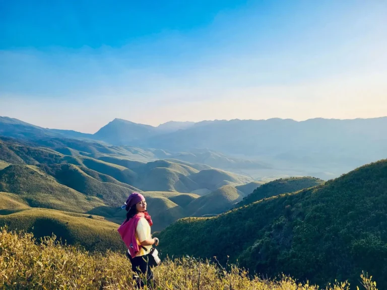 A girl enjoying the scenic view of Dzukou Valley hills
