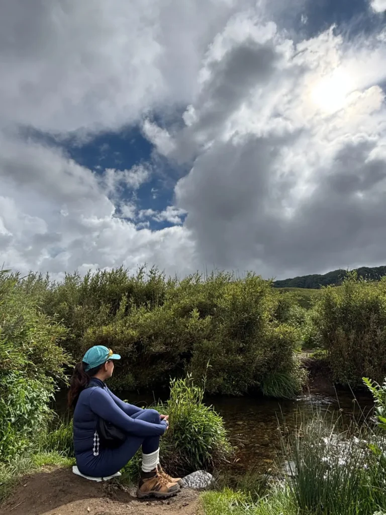 A girl sitting by a stream in Dzukou Valley