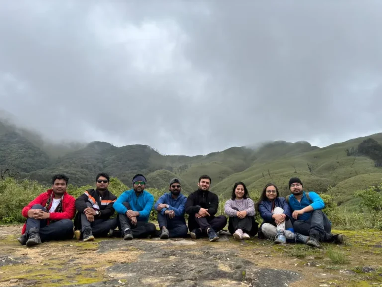 A group of people sitting together at Dzukou Valley with misty hills in the background