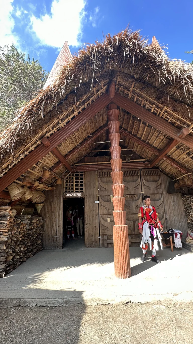 A traditional Chakhesang hut with a man in tribal attire at the Hornbill Festival