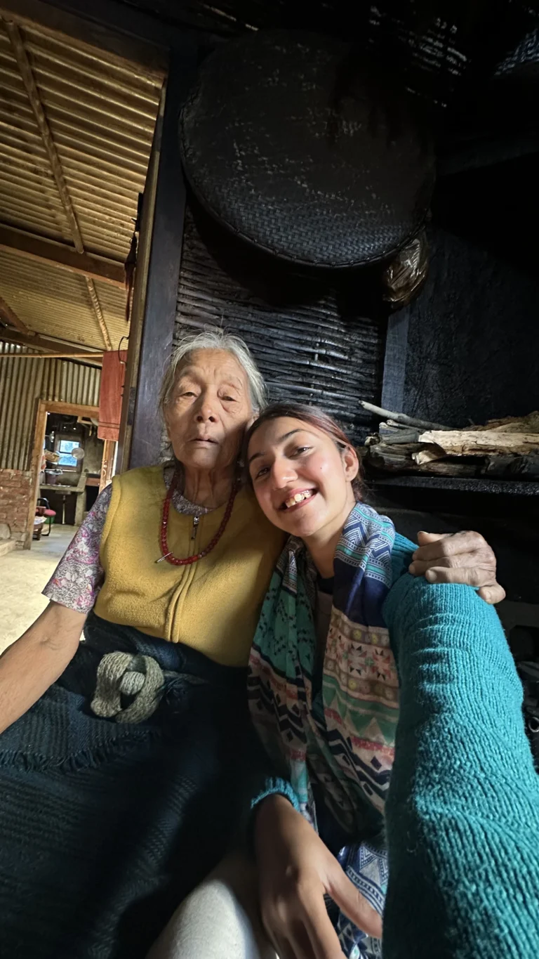 A young woman and an elderly Naga woman smiling together at the Hornbill Festival