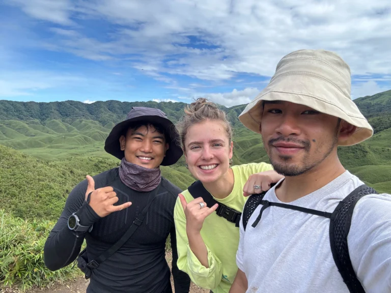 Group of friends smiling with the scenic hills of Dzukou Valley in the background