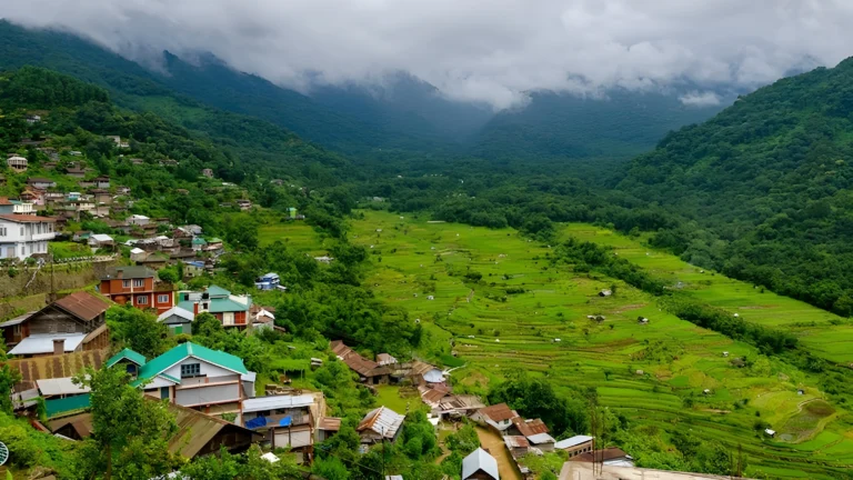 Khonoma village with colorful houses and green terraced fields under cloudy skies