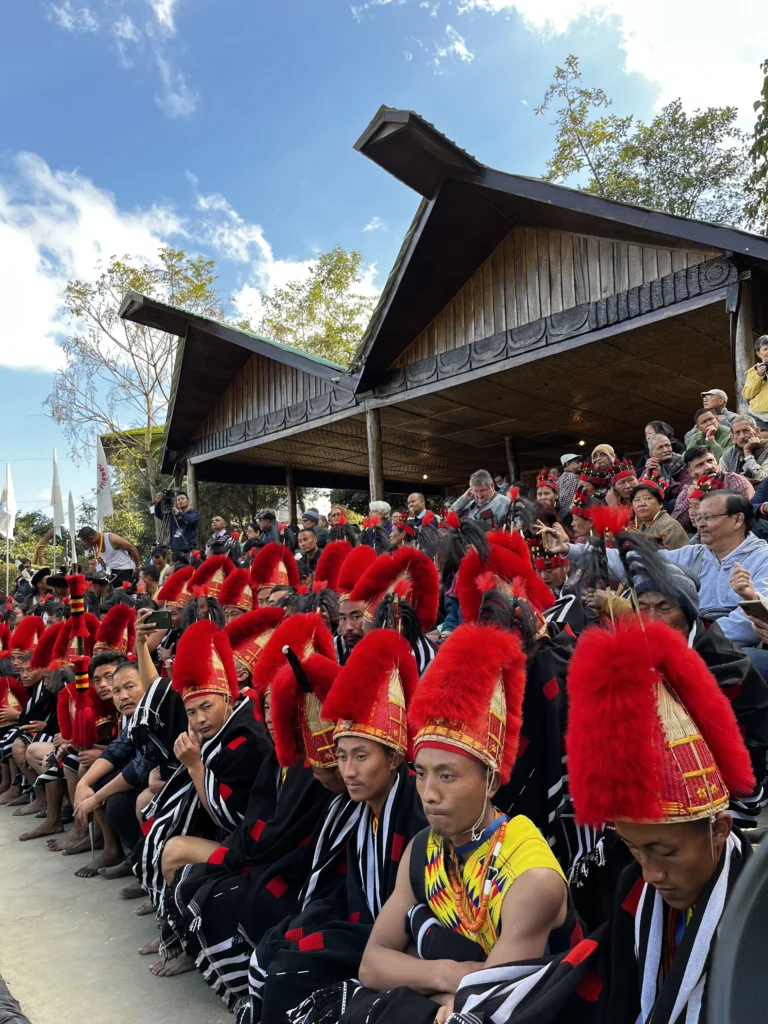 Naga men in red feathered headgear seated at the Hornbill Festival