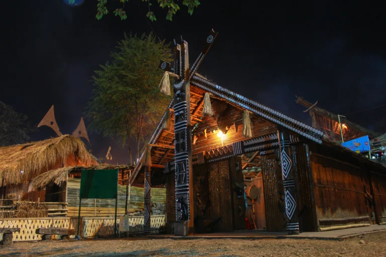 Traditional tribal hut lit up at night during the Hornbill Festival